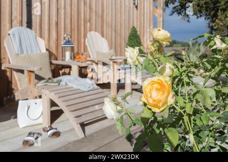 Hölzerne Liegestühle auf einer hölzernen Terrasse im Garten eines hölzernen Ferienhauses in Suffolk, Großbritannien Stockfoto