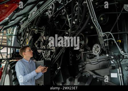 Servicemitarbeiter mit digitalem Tablet auf einem neben Ombinen-Harvester mit offener Haube. Stockfoto