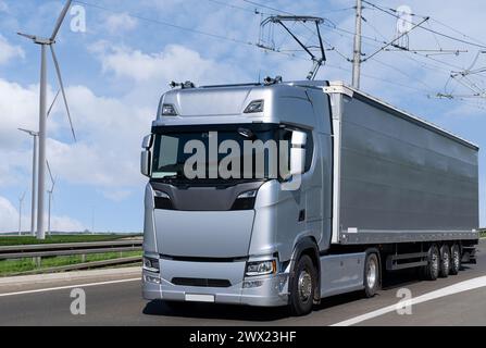 Der elektrische Sattelzugwagen mit Stromabnehmer nimmt Energie aus Kabeln über der Autobahn auf. Stockfoto