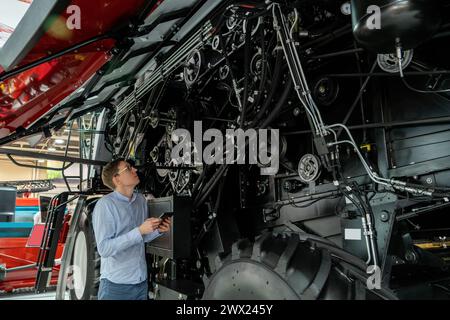 Servicemitarbeiter mit digitalem Tablet auf einem neben Ombinen-Harvester mit offener Haube. Stockfoto