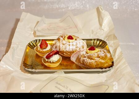 Italienisches Dessert Zeppole di San Giuseppe, Zeppola gebackene Puffs aus Choux-Gebäck, gefüllt und dekoriert mit Vanillecreme und Kirsche. Stockfoto
