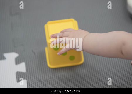 Das Kind greift während des Sitzens spielerisch mit Blöcken und anderen Spielzeugen in der Kinderbetreuung um. Enge Feldtiefe bei Nahaufnahmen der Hände des Neugeborenen Stockfoto