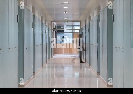 Mann, der auf dem Krankenhausflur läuft. Bewegungsunschärfe Langzeitaufnahme des Leuchtkorridors in der Klinik Stockfoto