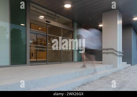 Eingang des Geschäftsgebäudes, insbesondere eines Krankenhauses. Langzeitaufnahme mit Bewegungsunschärfe eines Menschen, der die Treppe hinaufgeht Stockfoto