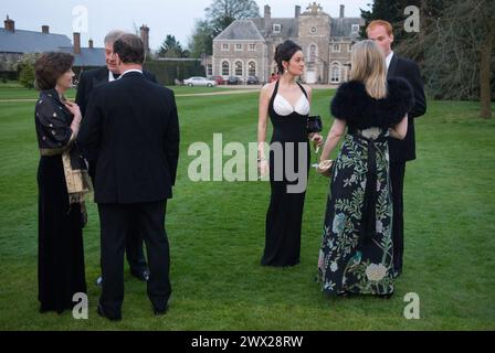 Eine junge Frau, die ein schwarz-weißes Abendkleid trägt, unter Freunden. Wohltätige Tanzgäste unterhalten sich in den Gärten, bevor sie in das Festzelt in den Gärten des Farleigh Wallop House, Farleigh Wallop, Hampshire, gehen. 2008 2000er Jahre UK HOMER SYKES Stockfoto