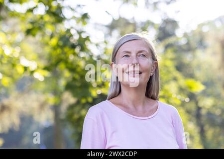 Nahaufnahme einer grauhaarigen älteren Frau, die im Park spaziert, lächelnd und atmend, während sie sich ausruht. Stockfoto