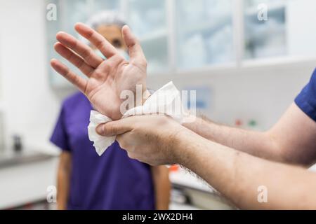 Tierarzt-Chirurg in Epi-Kleidung zur Vorbereitung der Handwaschung im Klinikwaschbecken Stockfoto