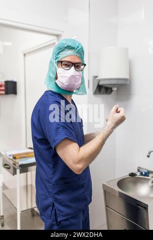 Tierarzt-Chirurg in Epi-Kleidung zur Vorbereitung der Handwaschung im Klinikwaschbecken Stockfoto