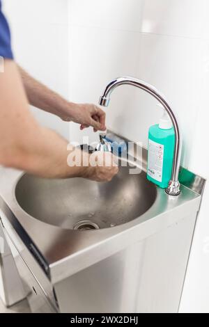 Tierarzt-Chirurg in Epi-Kleidung zur Vorbereitung der Handwaschung im Klinikwaschbecken Stockfoto