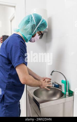 Tierarzt-Chirurg in Epi-Kleidung zur Vorbereitung der Handwaschung im Klinikwaschbecken Stockfoto