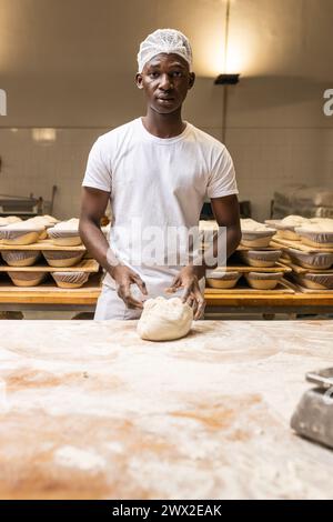 Junger schwarzer Mann, der in einer Brotfabrik arbeitet und das Handwerk lernt. Stockfoto