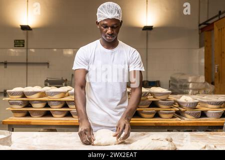 Junger schwarzer Mann, der in einer Brotfabrik arbeitet und das Handwerk lernt. Stockfoto