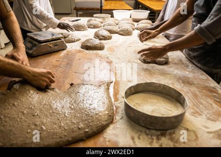 Multiethnische Gruppe von Kollegen, die in einer Brotfabrik arbeiten, Lehrlinge unterrichten, unerkennbare Menschen Stockfoto