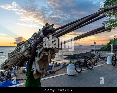 Salvador, Bahia, Brasilien - 01. Juni 2019: Strandarbeiter werden beim Sonnenuntergang am Strand von Porto da Barra in Salvador, Bahia, beim Transport von Material gesehen. Stockfoto