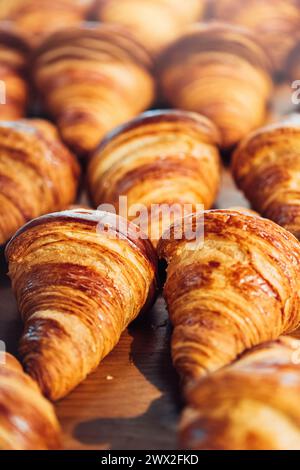 Eine Auswahl goldbrauner Croissants ist ordentlich auf einer Holzoberfläche angeordnet und zeigt ihre schuppige Textur und satte Farbe Stockfoto