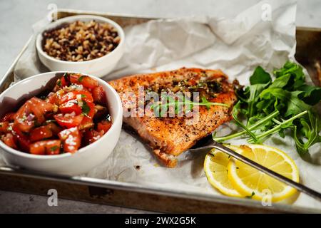 Gebackenes Lachsfilet, serviert mit Tomatensalat Quinoa-Reis und Rucola auf einem Blech Stockfoto