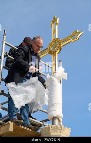 Nach fast zehn Jahren ist das Turmkreuz auf die evangelische Friedenskirche im Potsdamer Park Sanssouci zurueckgekehrt. Das im November 2014 aus Sicherheitsgruenden abgenommene mehr als drei Meter hohe Kreuz wurde am Mittwoch 27.03.2024 wieder auf dem Campanile, dem Glockenturm der Kirche, enthuellt. Foto: Frank Karalus, Projektleitung, Abteilung Baudenkmalpflege und Liegenschaften, SPSG, enfernt die Schutzhuelle der 1850 errichteter Turm wird seit Februar 2022 saniert. Das Dach des rund 42 Meter hohe Campanile sei mittlerweile instand gesetzt und mit Zinkblech neu eingedeckt, hiess es von der S Stockfoto