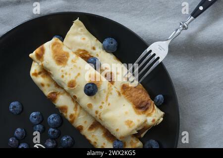 Obstpfannkuchen mit Gabel auf einem schwarzen Teller - Blick von oben. Stockfoto