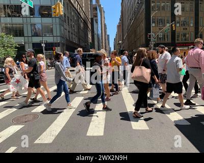 Fußgänger und Reisende gehen und überqueren die Straße während der Mittagspause in New York City Stockfoto