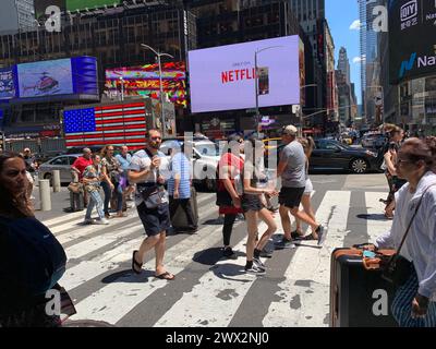 Touristenspaziergang durch den Times Square in New York vorbei an Video-Plakatwänden und Werbung Stockfoto