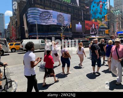 An einem sonnigen Sommertag laufen Fußgänger über die Straße am New York City Times Square Stockfoto