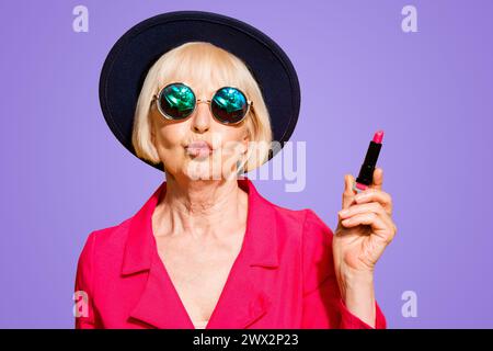 Großmutter macht sich bereit für ein Date charmante, attraktive alte Frau mit roten Lippenstift, die schmollende Lippen für einen Kuss isoliert auf brigthgelbem Hintergrund hält Stockfoto