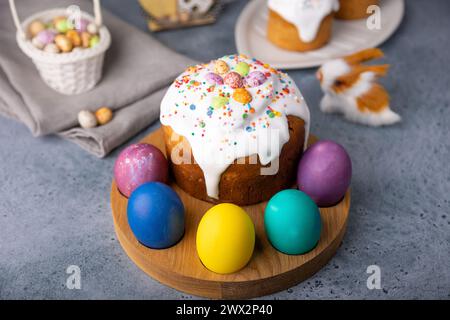 Osterkulich mit kandierten Früchten in weißer Glasur mit bunten Streuseln und bemalten Eiern. Traditionelles Ostergebäck. Osterferien. Nahaufnahme, wählen Sie Stockfoto