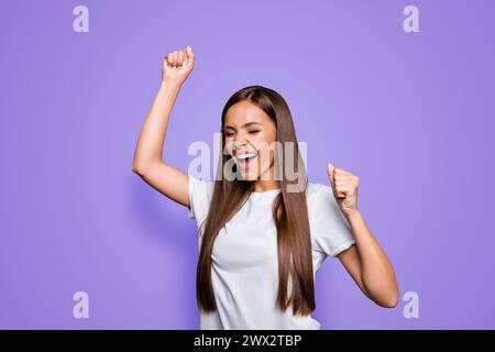 Porträt einer braunhaarigen, attraktiven, netten, aufgeregten jungen Dame, die den Sieg feiert, vor grauem Hintergrund, isoliert Stockfoto