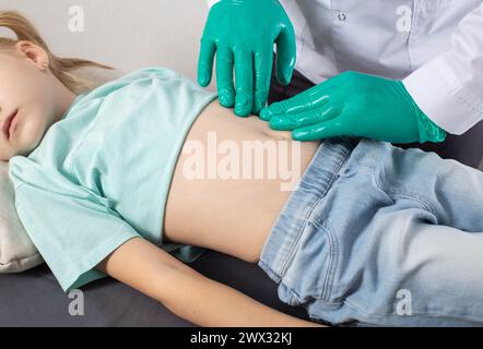 Ein Gastroenterologe palpiert den Bauch eines siebenjährigen Mädchens. Bauchschmerzen bei Kindern. Erkrankungen der Milz und des Pankreas, Pankreatit Stockfoto