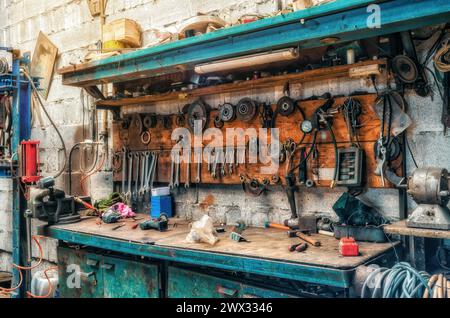 Vintage-Werkstatt. Antike Werkzeuge hängen an der Wand, reparieren Ausrüstung auf dem Tisch. Seitenansicht. Stockfoto