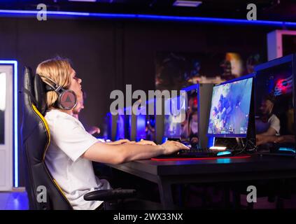 Ernsthaft fokussierter, pimply Teenager-Gamer im Headset, der PC-Videospiel im Computerclub mit Team-Cyber-Sport-Turnier spielt. E-Sport-Meisterschaft. Stockfoto