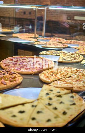 Lebendiges Bild mit einer Vielzahl köstlicher und frisch zubereiteter Pizzen, die in einer Pizzeria mit einer warmen und gemütlichen Atmosphäre präsentiert werden, ideal für Pizzaliebhaber. Stockfoto