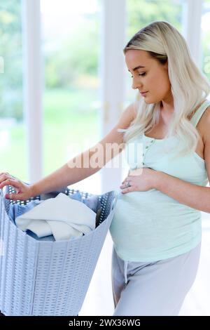 Müde schwangere Frau mit Waschkorb Stockfoto