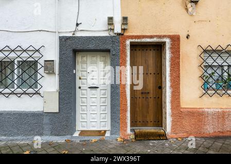 Alte zweistöckige mehrfarbige Häuser mit Metallstangen an den Fenstern in einer Fußgängerzone mit herkömmlichen Gehwegen Stockfoto