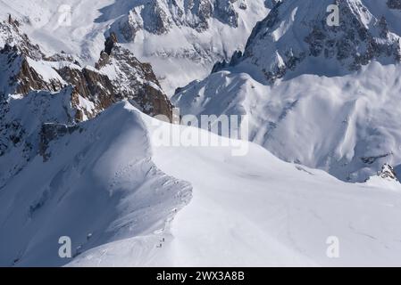 Gruppen von Skifahrern, die auf einem schneebedeckten Bergrücken in die Vallee Blanche im Mont Blanc-Massiv in Chamonix in Frankreich fahren Stockfoto