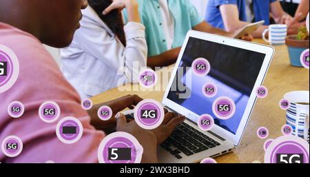 Bild von 5g-Texten mit Symbolen über einem afroamerikanischen Mann, der im Büro am Laptop arbeitet. Digital Composite, Mehrfachbelichtung, Unternehmen, Telekommunikation Stockfoto