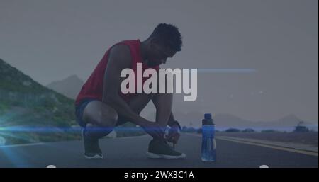 Bild: Blaue Lichtspuren gegen afroamerikanische FIT-Männer, die Schnürsenkel auf der Straße binden. Sport- und Fitnesstechnik-Konzept Stockfoto