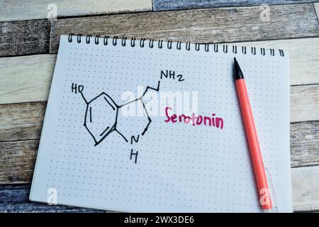 Konzept der chemischen Molekülformel Hormon Serotonin Schrift auf Buch isoliert auf Holztisch. Stockfoto
