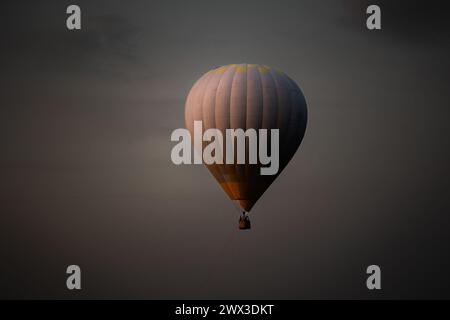 Heißluftballon mit hell brennender Flamme, die in der Nacht fliegt. Stockfoto
