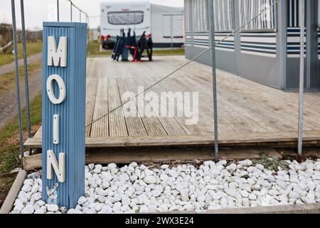 Damp, Deutschland. März 2024. Eine Säule mit dem Wort „Moin“ steht vor einem Wohnwagen auf dem Campingplatz Ostseecamping in Schubystrand. Pünktlich zu Ostern kommen die ersten Gäste der Saison auf den Campingplätzen an Nord- und Ostsee sowie im Landesinneren Schleswig-Holsteins an. Frank Molter/dpa/Alamy Live News Stockfoto