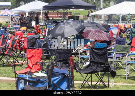 Suwanee, GA / USA - 12. August 2023: Zwei Menschen schützen die sengende Hitze mit Regenschirmen, während sie auf ein Sommerkonzert warten. Stockfoto