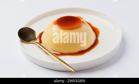 Panna Cotta mit Karamellsauce auf einem weißen Teller mit einem Löffel Stockfoto