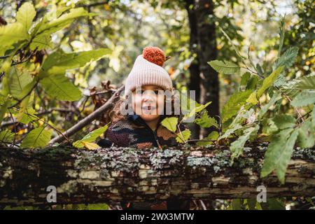 Porträt eines modischen kleinen Jungen mit Hut, der glücklich auf einem Waldweg spielt, während er seinen Eltern etwas über Pflanzen beibringt Stockfoto