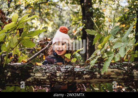 Porträt eines modischen kleinen Jungen mit Hut, der glücklich auf einem Waldweg spielt, während er seinen Eltern etwas über Pflanzen beibringt Stockfoto