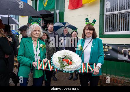 Zwei Damen tragen einen irischen Kranz vom Warrington Irish Club am St. Patrick's Day 2024 Stockfoto