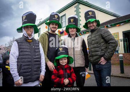 4 junge Männer und ein kleiner Junge tragen große Guinness-Hüte vor dem Warrington Irish Club am St. Patrick's Day 2024 Stockfoto