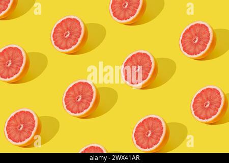 Trendiges Sonnenlicht-Fruchtmuster mit roter Grapefruitscheibe auf gelbem Hintergrund. Minimales Sommerkonzept. Kreative Essensidee. Grapefruitästhetik. Stockfoto