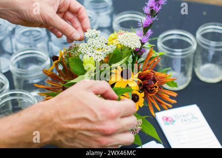 Ein Blumenhändler schneidet im Sommer wilde Blumen, während er im Freien ein Blumenarrangement anfertigt. Stockfoto