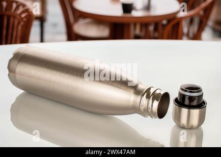 Eine Thermosflasche aus Metall auf einem Tisch in einem Café, Nahaufnahme. Stockfoto