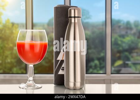 Eine Thermosflasche aus Metall mit einer Papierkarton und einem Glas Tomatensaft steht in Nahaufnahme auf dem Tisch vor dem Hintergrund des Fensters. Stockfoto